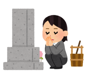お墓の前で手を合わせる女性