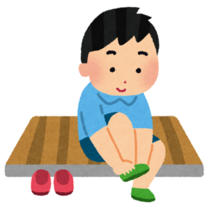 上がり口で靴から上履きに履き替える子ども